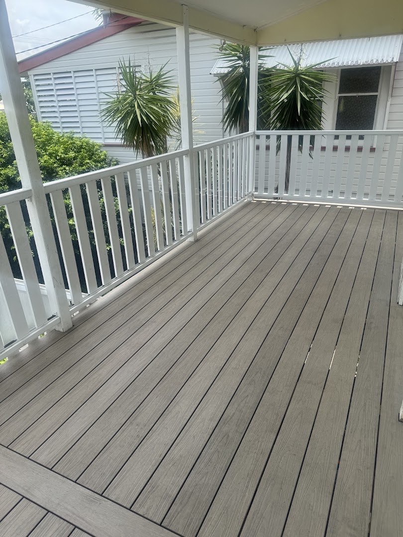 A timber deck with a white balustrade running along the side of a raised home