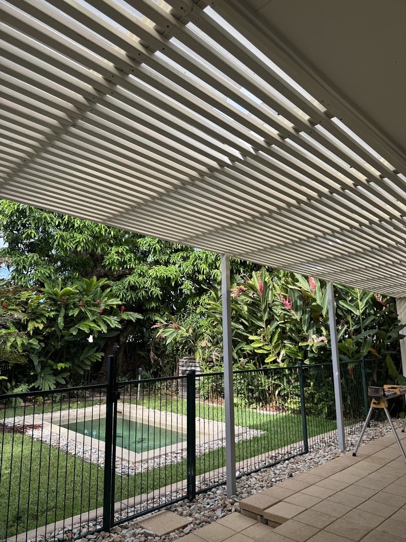 A white slatted timber patio roof over an outdoor area beside a pool